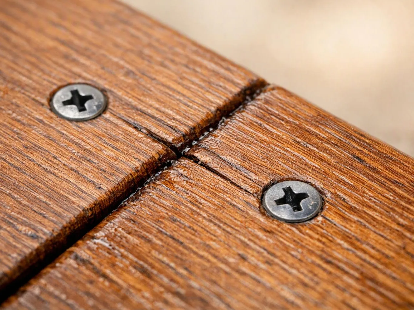 Close-up of two screws fastening textured wooden boards together with a narrow gap between them