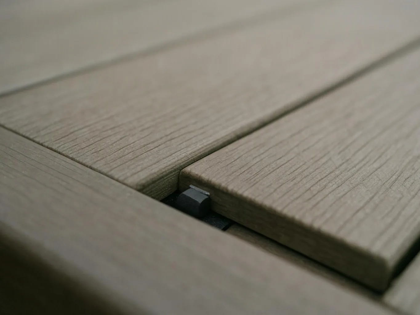 Close-up of weathered wooden boards joined with a small black spacer in the gap