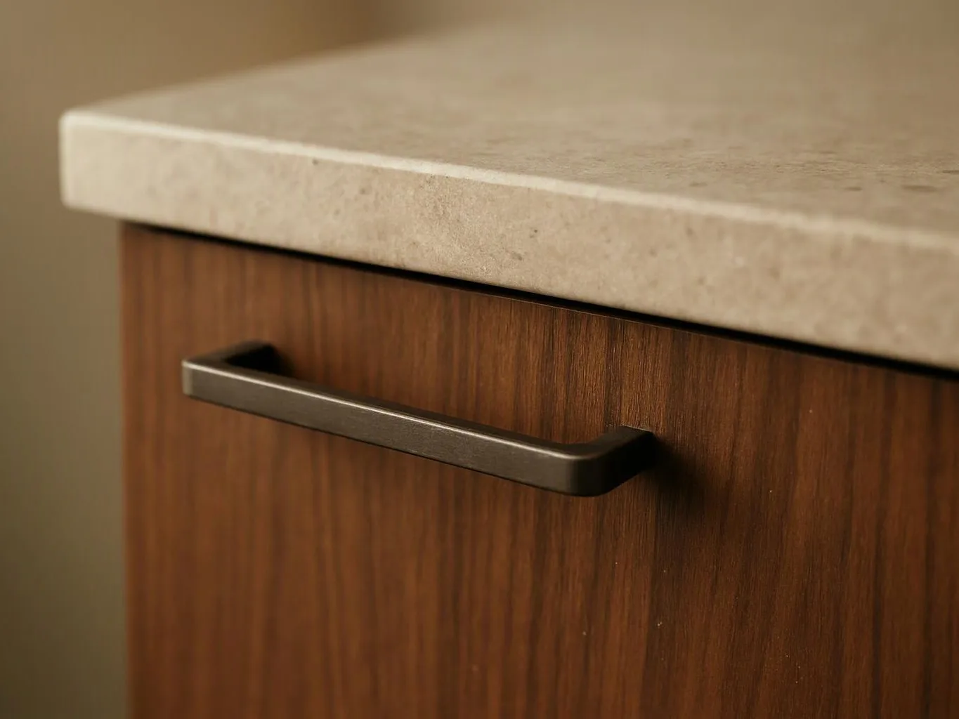 Close-up of a wooden cabinet with a stone countertop and a dark metal drawer handle